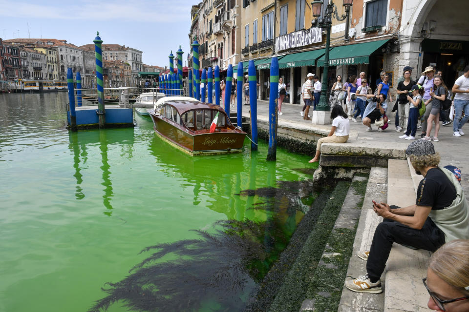 People look at Venice's historical Grand Canal as a patch of phosphorescent green liquid spreads in it, Sunday, May 28, 2023. The governor of the Veneto region, Luca Zaia, said that officials had requested the police to investigate to determine who was responsible, as environmental authorities were also testing the water. (AP Photo/Luigi Costantini)