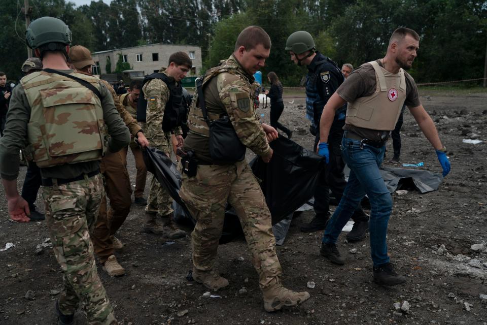Ukrainian servicemen carry a bag containing a person's body after a Russian attack in Zaporizhzhia, Ukraine, Friday, Sept. 30, 2022.