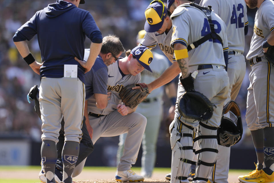 Milwaukee Brewers relief pitcher Gus Varland, center, reacts after being hit by a comebacker from San Diego Padres' Manny Machado during the eighth inning of a baseball game Saturday, April 15, 2023, in San Diego. (AP Photo/Gregory Bull)