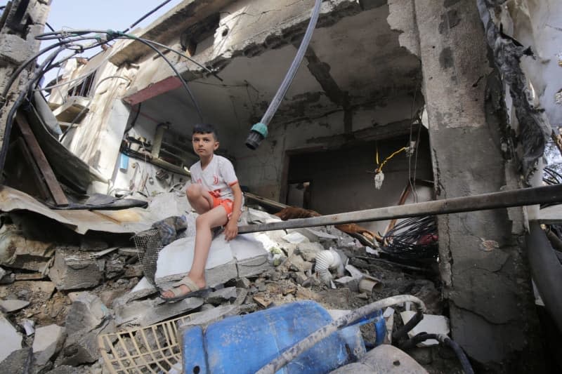 A Palestinian child collects his belongings from destroyed buildings after the Israeli army's airstrike at Nuseirat Refugee Camp. Omar Ashtawy/APA Images via ZUMA Press Wire/dpa