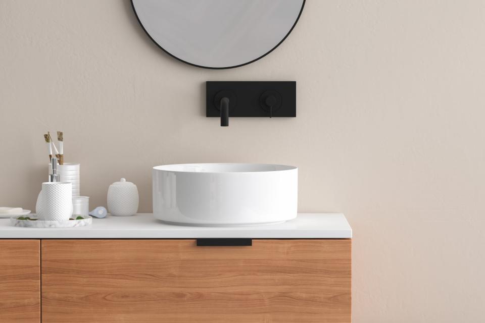 Close up of sink with oval mirror standing in on beige wal