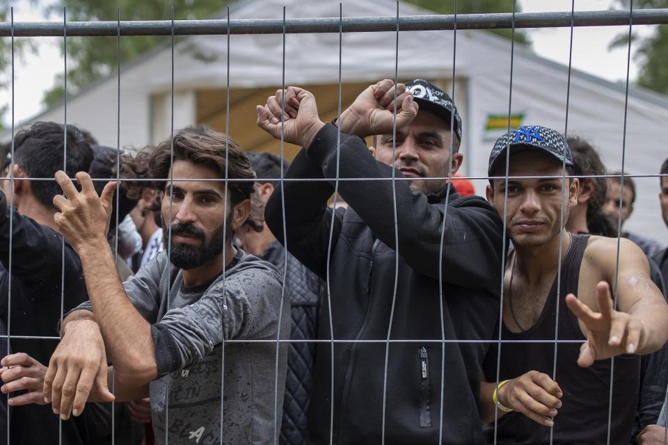 FILE - In this file photo taken on Wednesday, Aug. 4, 2021, Migrants stand behind a fence inside the newly built refugee camp in the Rudninkai military training ground, some 38km (23,6 miles) south from Vilnius, Lithuania. Lithuanian authorities said Friday that the Baltic country has stemmed the flow of third country migrants illegally crossing from neighboring Belarus, saying the influx of people knocking at the external border of European Union seems to have halted and hundreds have been turned away. These people have a completely different culture. That's why we are worried about this," said local resident Kristina Slovenska. "We are worried about our safety." (AP Photo/Mindaugas Kulbis, File)