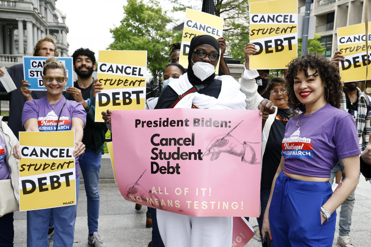 Student loan activists at a rally hold signs reading: Cancel student debt.