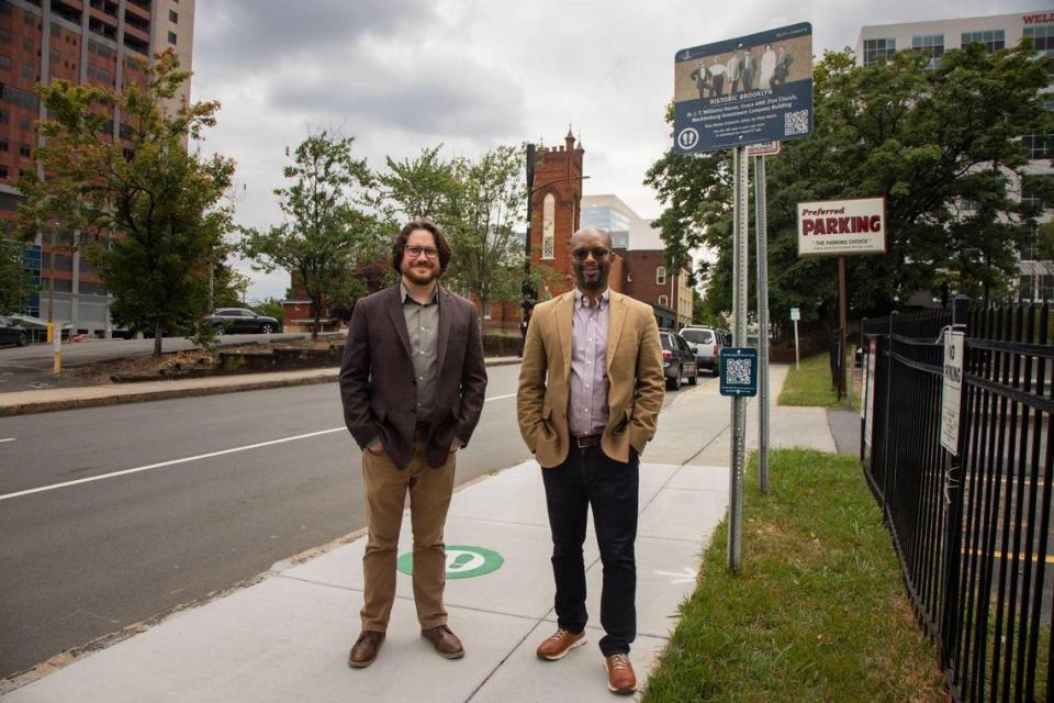 The Levine museum’s Willie Griffin and Eric Scott stand in front of one of the virtual landmarks that give people a chance to learn about the history of the Brooklyn neighborhood in Charlotte via a new app from the museum.