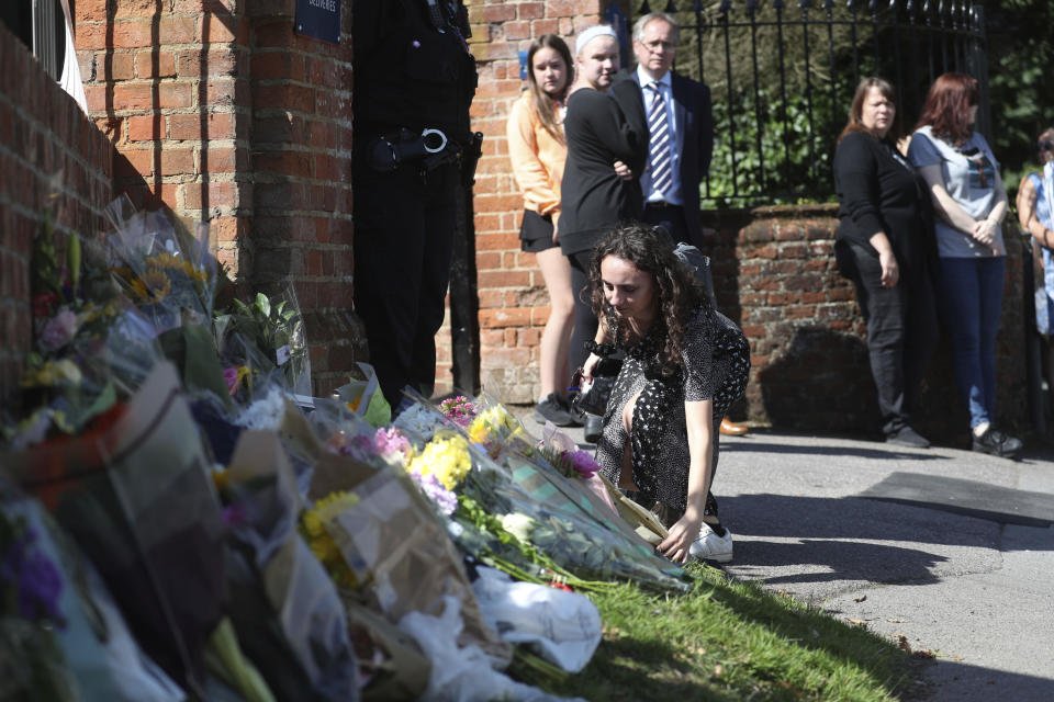 Flowers are placed at the entrance to the Holt School, in Wokingham, England, in memory of teacher James Furlong, a victim of a terror attack in nearby Reading, Monday June 22, 2020.  A lone terror suspect remains in custody accused of killing three people and wounding three others in a Reading park on Saturday night. (Steve Parsons/PA via AP)