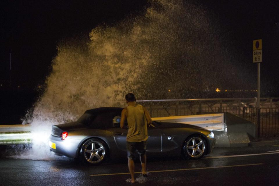 A man tries to get back into his car as a wave surges past a barrier on the shore during Typhoon Usagi in Hong Kong September 22, 2013. Typhoon Usagi, the strongest storm to hit the Western Pacific this year, headed towards the southern Chinese city of Hong Kong, one of the most densely populated cities on Earth, on Sunday amid warnings of severe flooding as well as strong winds in the event of a direct hit. REUTERS/Tyrone Siu