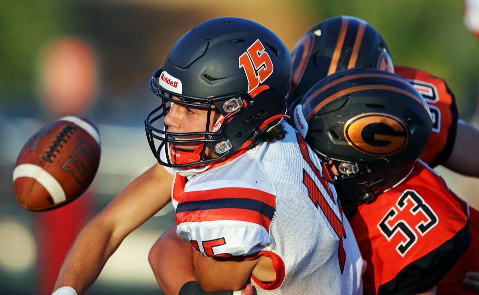 Ellet quarterback Jake Flossie fumbles the ball as he is brought down by Green defensive lineman Michael Schaal during the first half of a high school football game, Friday, Aug. 19, 2022, in Green, Ohio.