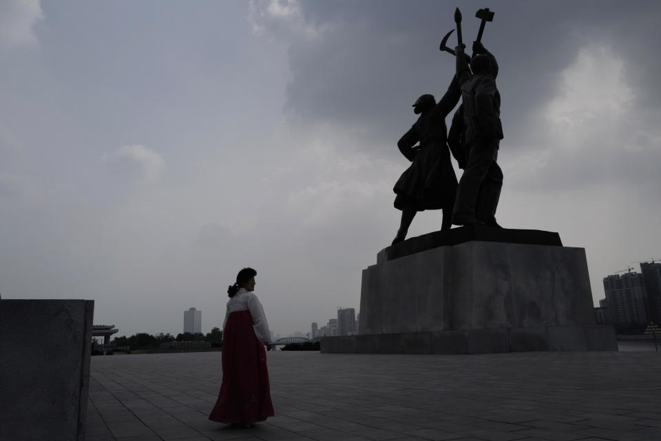 In this July 15, 2019, photo, a North Korean tourist guide walks past a statue in front of the Tower of Juche Idea in Pyongyang, North Korea. The word Juche is splashed across countless propaganda signs in North Korea and featured in hundreds of state media reports, and while it’s technically a political ideology, it can seem more like a religion because of its difficulty for many outsiders to grasp and ability to inspire devotion among North Koreans. (AP Photo/Vincent Yu)