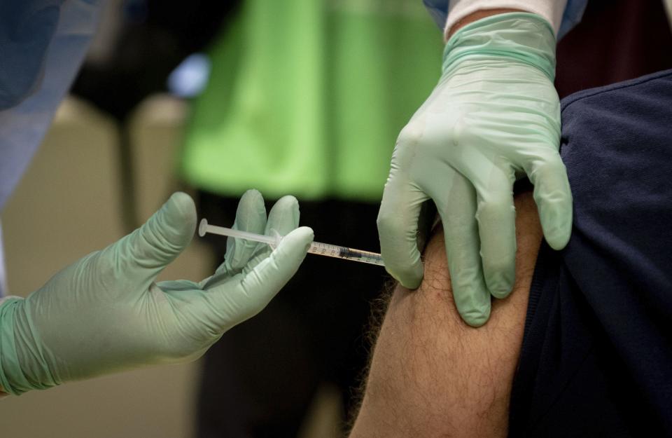 A doctor vaccinates a caregiver at the fourth vaccination center in Berlin, located in Terminal C of the former Tegel Airport, Germany, Wednesday, Feb.10, 2021. Here, at the beginning, mainly nurses and medical staff are vaccinated against the coronavirus. (Nietfeld/dpa via AP)