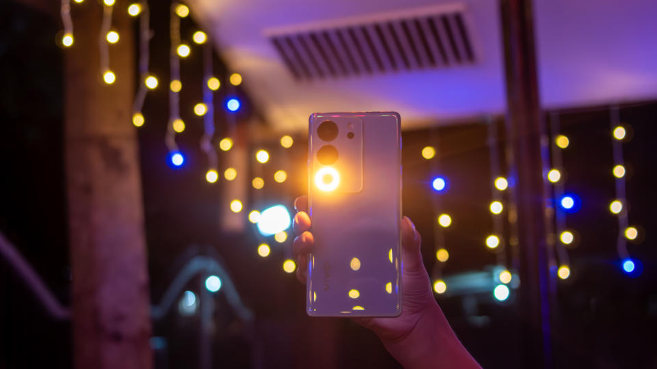 A smartphone in hand, surrounded by a mesmerizing backdrop of vibrant lights