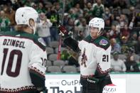 Arizona Coyotes' Ryan Dzingel (10) looks on as teammate Loui Eriksson (21) acknowledges cheers from fans after being recognized for participating in his 1000th career game in the first period of an NHL hockey game against the Dallas Stars in Dallas, Monday, Dec. 6, 2021. (AP Photo/Tony Gutierrez)