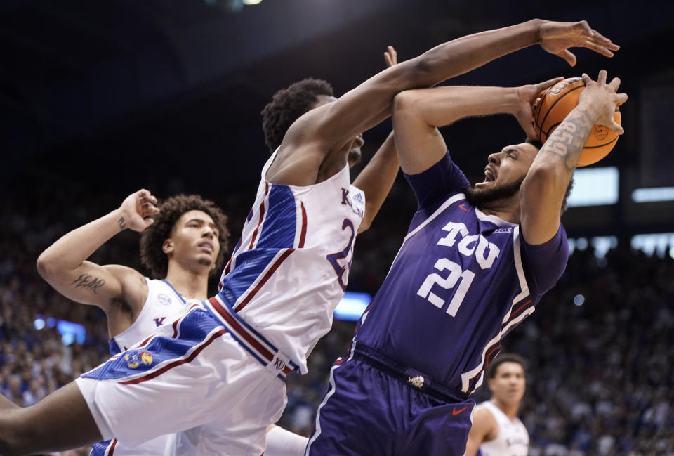 TCU forward JaKobe Coles (21) hangs back for a shot as Kansas center Ernest Udeh Jr. (23) defends during the second half of an NCAA college basketball game on Saturday, Jan. 21, 2023, at Allen Fieldhouse in Lawrence, Kan. TCU defeated Kansas, 83-60. (AP Photo/Nick Krug)