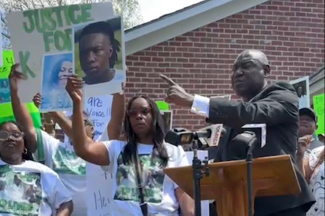 <p>Instagram/attorneycrump</p> KayChia Calvert (left, holding headshot of her deceased son, Kadarius Smith) stands alongside civil rights lawyer Ben Crump (speaking at podium).