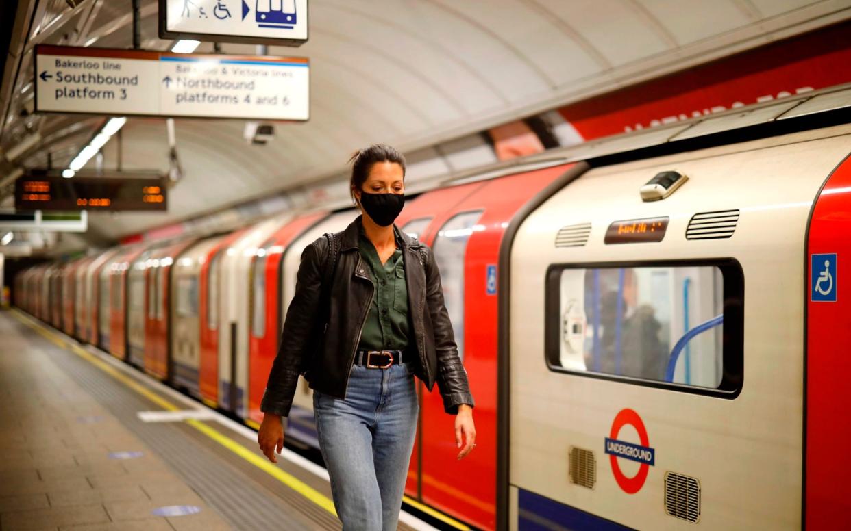 A commuter wears a face mask as she disembarks at a tube station in London - Tolga Akmen/AFP