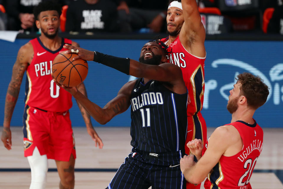 James Ennis III #11 of the Orlando Magic is fouled by Nicolo Melli #20 of the New Orleans Pelicans as he shoots against Josh Hart #3 during the second half of an NBA basketball game at the ESPN Wide World Of Sports Complex.