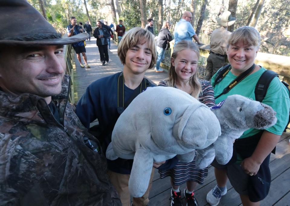 The Klein family -- dad Tim, Caleb, Kaia and mom Angie -- show off their plush manatees as they join the crowd checking out the real manatees packed into the spring run for the warm wate Thursday at Blue Spring State Park.