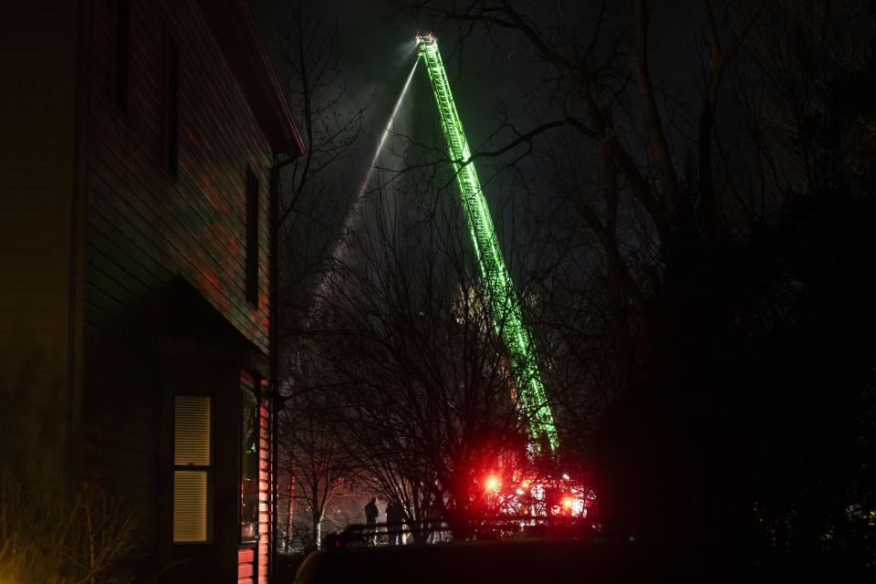 An Arlington County Fire Department ladder truck sprays water down on the remains of a house that exploded on Monday, Dec. 4, 2023, in Arlington, Va. (AP Photo/Kevin Wolf)