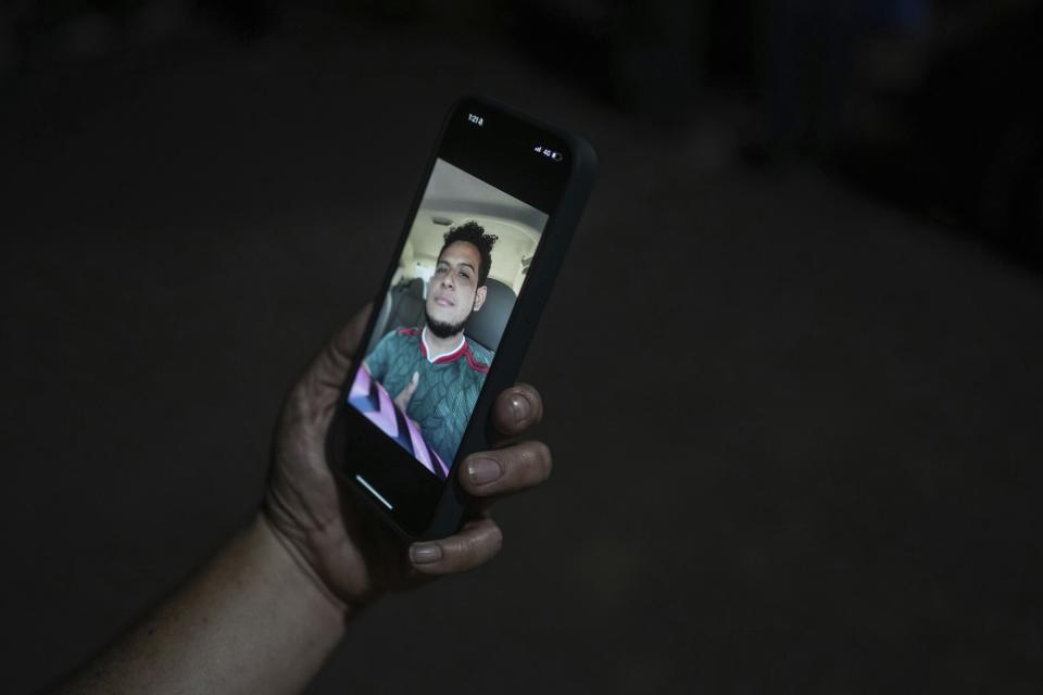 A relative holds a smartphone displaying a photo of Brando Arellano Cruz, fatally shot by police after he failed to pull over, in Lerdo de Tejada near Veracruz, México, Saturday, Jan. 19, 2024. Four municipal police officers are under investigation in relation to the death of the young man, after the victim's neighbors staged violent protests and attempted to lynch the officers. (AP Photo/Felix Marquez)