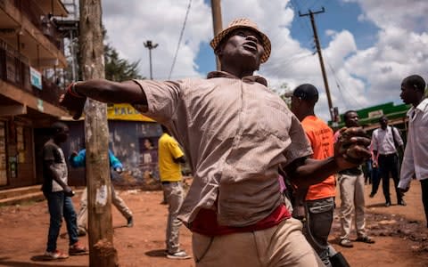 A protester hurls a stone at the police during a standoff between Kenyan police and supporters of Kenyan opposition leader - Credit: FREDRIK LERNERYD/ AFP