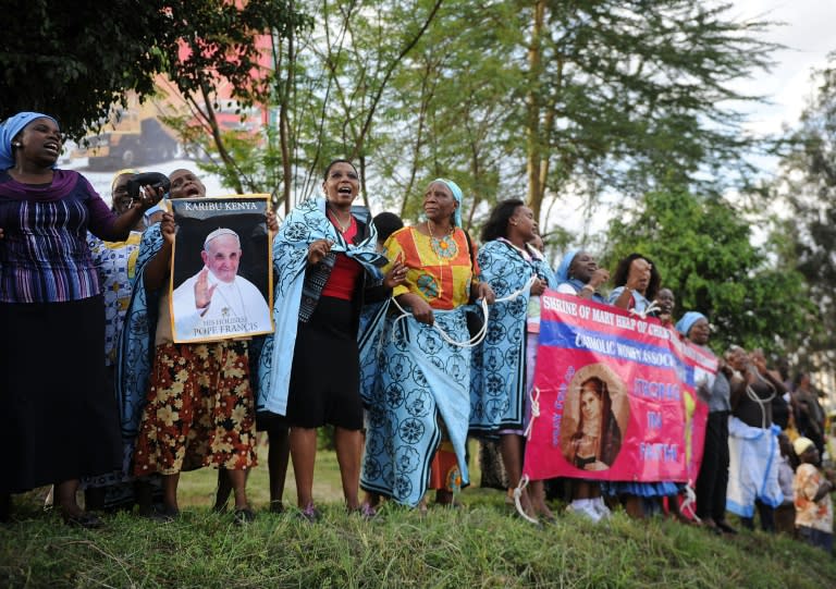 Catholics sing by the roadside carrying posters and welcome-banners for Pope Francis as they wait for his motorcade in the Kenyan capital, Nairobi November 25, 2015