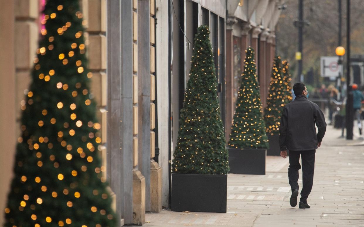 a man walks past Christmas lights in London - dominic lipinski/pa