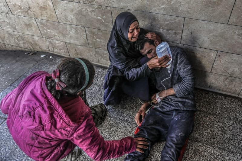 A Palestinian woman holds a glucose solution for her relative, who was injured in an Israeli air strike near a warehouse of the United Nations Relief and Works Agency for Palestine Refugees (UNRWA), at Al-Najjar Hospital in Rafah, southern Gaza Strip. Abed Rahim Khatib/dpa