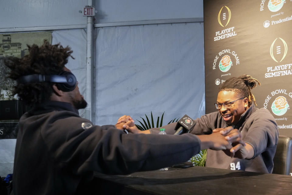 Michigan defensive lineman Kris Jenkins, right, greets teammate defensive back Brandyn Hillman during media day Saturday, Dec. 30, 2023, in Pasadena, Calif. Michigan is scheduled to play against Alabama on New Year's Day in the Rose Bowl, a semifinal in the College Football Playoff. (AP Photo/Ryan Sun)