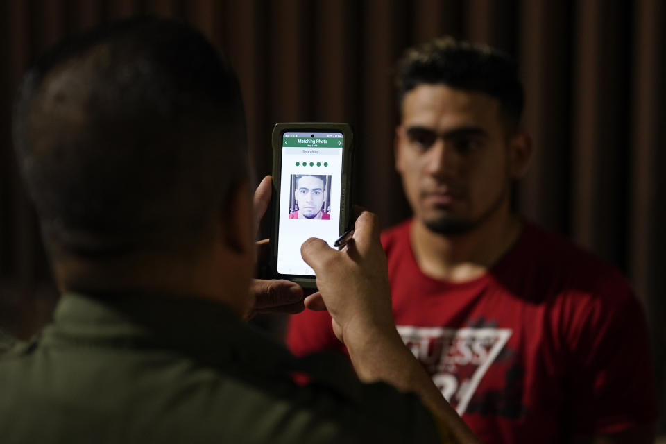 A migrant is processed by a Border Patrol agent near the end of a border wall Tuesday, Aug. 23, 2022, near Yuma, Arizona. The Border Patrol is seeing a dramatic shift in the type of migrants who come across the busiest places on the U.S.-Mexico. Migrants are now coming from more than 100 countries, and Mexicans are virtually absent. (AP Photo/Gregory Bull)