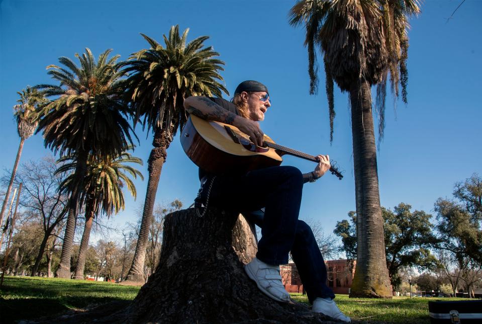 Johnny Arrow takes advantage of the relatively warm sunshine Feb. 23 to sing along with his guitar as he sits on a tree stump at Victory Park in Stockton. "I was sitting at home and said to myself 'why am I sitting here,' " Arrow said, when he decided to take in the nice day at the park. He enjoyed watching the people walking and jogging by as he sang and played.