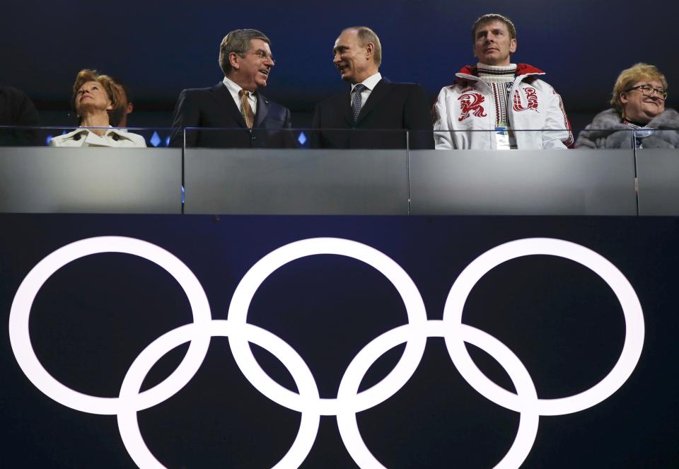 IOC President Bach speaks with Russian President Putin as gold medallist in the four-man bobsleigh Zubkov looks on during the closing ceremony for the 2014 Sochi Winter Olympics