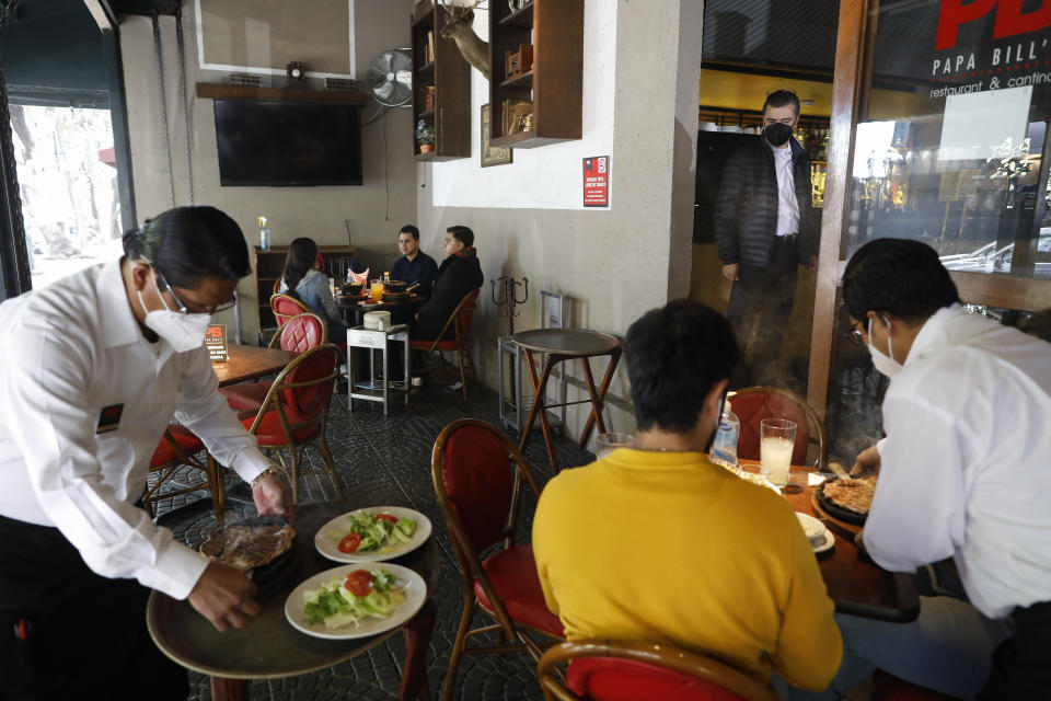 Diners eat at distanced outdoor tables at Papa Bill's restaurant in the Cuauhtemoc neighborhood of Mexico City, Monday, Jan. 11, 2021. More than three weeks into Mexico City's second pandemic shutdown some restaurateurs worried about their ability to survive ignored official warnings and opened limited seating Monday under the slogan, "Abrir o Morir," Spanish for "Open or Die." (AP Photo/Rebecca Blackwell)