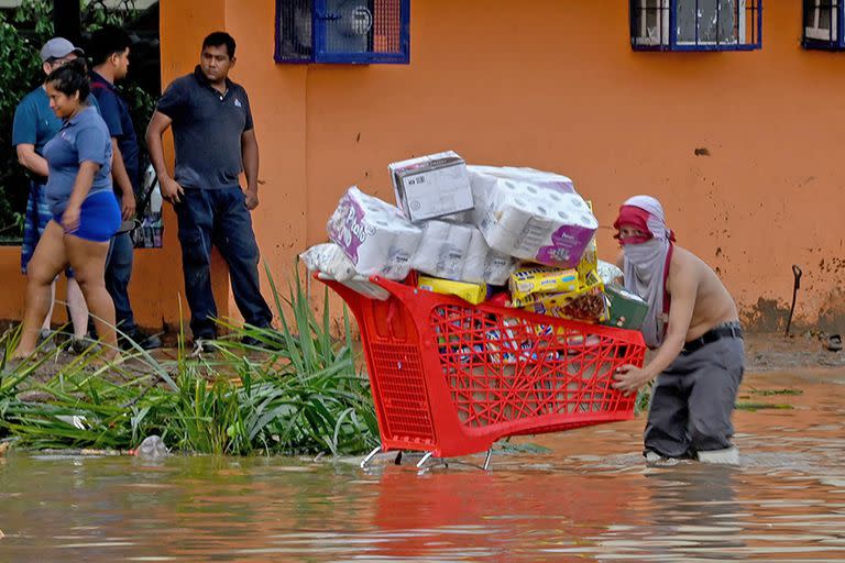 Un hombre lleva un carro lleno de bienes robados de un supermercado después del paso del huracán Otis en Acapulco, estado de Guerrero, México, el 25 de octubre de 2023