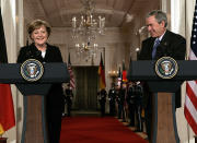 FILE - President George W. Bush and German Chancellor Angela Merkel, left, laugh during a joint news conference at the White House on Jan. 13, 2006, in Washington. Merkel has been credited with raising Germany’s profile and influence, helping hold a fractious European Union together, managing a string of crises and being a role model for women in a near-record tenure. Her designated successor, Olaf Scholz, is expected to take office Wednesday, Dec. 8, 2021. ​(AP Photo/Evan Vucci, File)