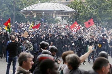 Masked youths with labour union flags are seen during clashes with French gendarmes and riot police during a demonstration in protest of the government's proposed labor law reforms in Paris, France, May 26, 2016. REUTERS/Charles Platiau