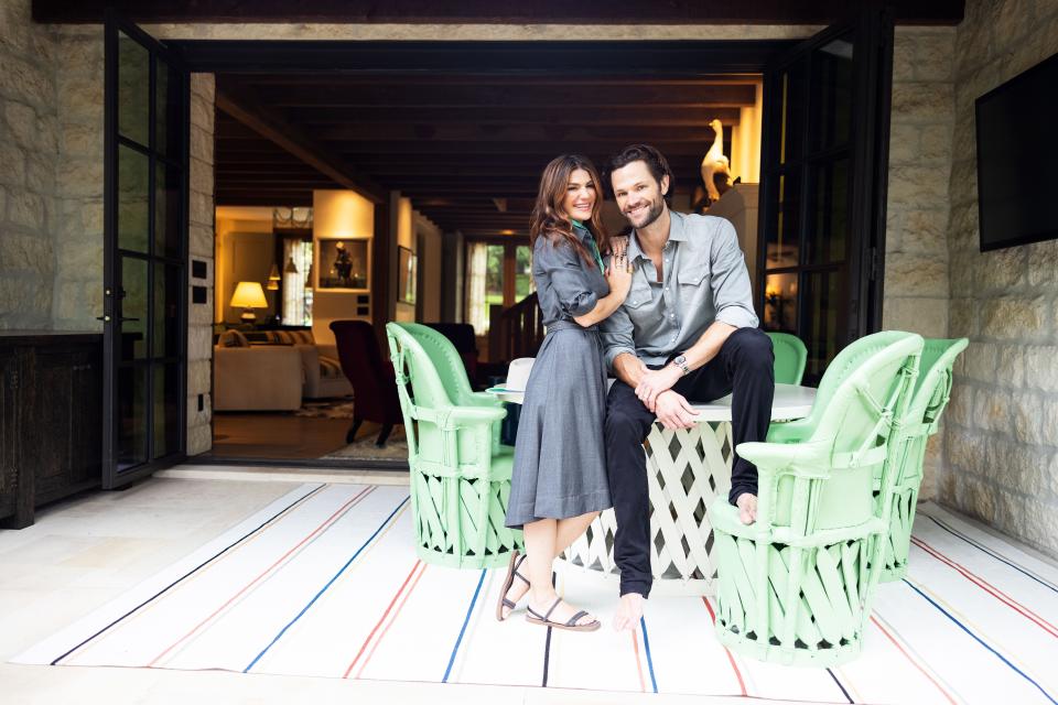 Jared and Genevieve pictured in one of the outdoor areas of the home. The minty green painted table and chairs are placed atop a Perennials outdoor rug.