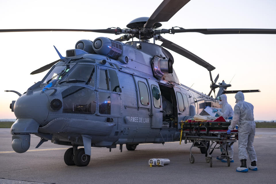 In this photo provided by the French Army Thursday, April 2, 2020, medical staffs evacuate a patient infected with the Covid-19 virus, Wednesday April 1, 2020 at Orly airport, south of Paris. The operation aims at relieving hospitals in the Paris region, hardly hit by the coronavirus. The new coronavirus causes mild or moderate symptoms for most people, but for some, especially older adults and people with existing health problems, it can cause more severe illness or death. (Julien Fechter/DICOD via AP)