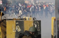 Protesting farmers throw stones at the police during a clash at the Delhi Haryana state border, India, Friday, Nov. 27, 2020. Thousands of agitating farmers in India faced tear gas and baton charge from police on Friday after they resumed their march to the capital against new farming laws that they fear will give more power to corporations and reduce their earnings. While trying to march towards New Delhi, the farmers, using their tractors, cleared concrete blockades, walls of shipping containers and horizontally parked trucks after police had set them up as barricades and dug trenches on highways to block roads leading to the capital. (AP Photo/Manish Swarup)