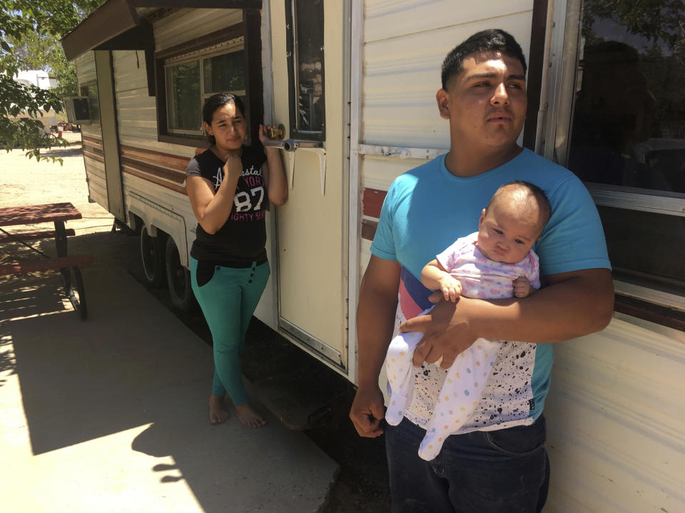 In this May 25, 2018 photo, Jose Espinoza, 18, stands out his trailer with his 4-month-old infant, Emmily, and wife, Maria Rodriguez, 19, in Vado, N.M. while speaking about making only $50 a day picking onions. The U.S. Census Bureau is using new high tech tools like aerial imagery to help get an accurate 2020 Census and avoid undercounting communities struggling with poverty. (AP Photo/Russell Contreras)