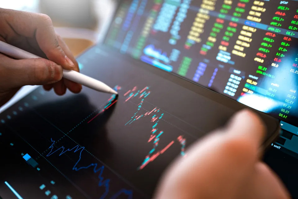 Market Analyze with Digital Monitor focus on tip of finger.