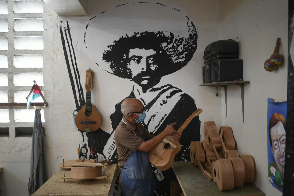 A mural of Mexican revolutionary hero Emiliano Zapata decorates the Jacinto Perez lutherie school where Jose Luis Reyna teaches students to build their own traditional Venezuelan instrument called "el cuatro" in the 23 de Enero neighborhood of Caracas, Venezuela, Wednesday, May 26, 2021. Due to the COVID-19 pandemic lockdown, students can only come every other week to work on their instruments, making the process much slower. (AP Photo/Matias Delacroix)