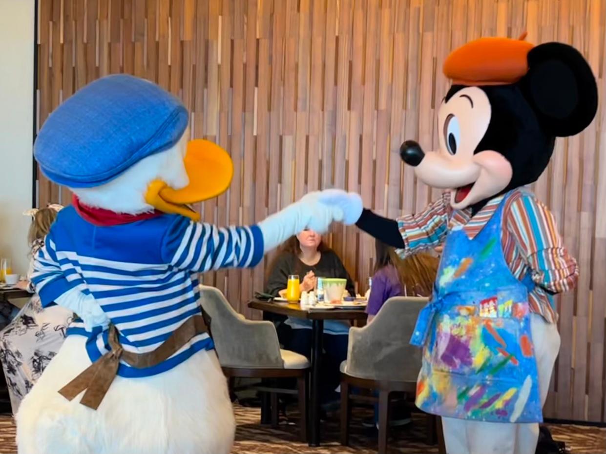 Donald Duck and Mickey Mouse shake hands at Topolino's Terrace.