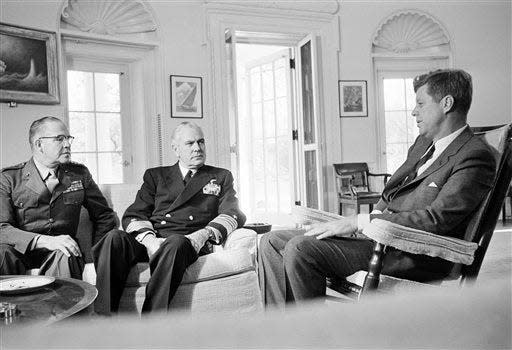 File - In this Oct. 29, 1962, file photo, President John F. Kennedy poses in the White House office with Gen. David Shoup, left, Marine Corps Commandant, and Adm. George Anderson, Chief of U.S. Naval Operations in Washington. The chiefs met with the president to review the situation in Cuba and operation of the U.S. naval blockade.  As the U.S. and Russia reached the brink of nuclear war in 1962, Kennedy received top-secret intelligence from the CIA that a new warhead launcher was spotted in Cuba. That report, given to Kennedy a day before the end of the Cuban Missile Crisis, is among roughly 19,000 pages of newly declassified CIA documents from the Cold War released Wednesday, Sept. 16, 2015. (AP Photo/William J. Smith, File)