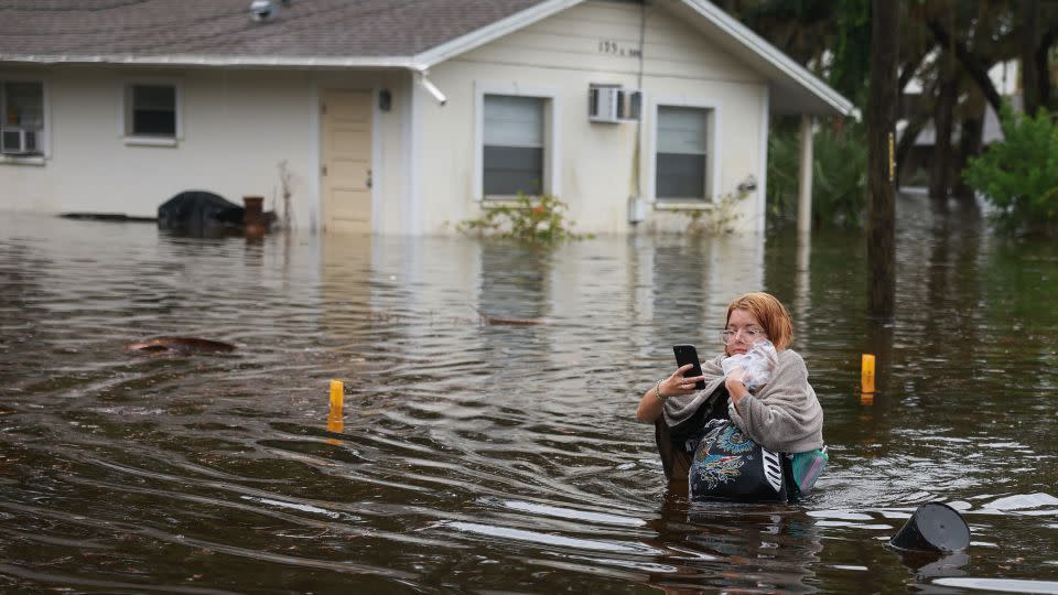 2023 年 8 月 30 日，飓风伊达利亚过后，马卡特拉·里奇特 (Makatla Ritchter) 在佛罗里达州塔彭斯普林斯 (Tarpon Springs) 趟过洪水。- Joe Raedle/Getty Images