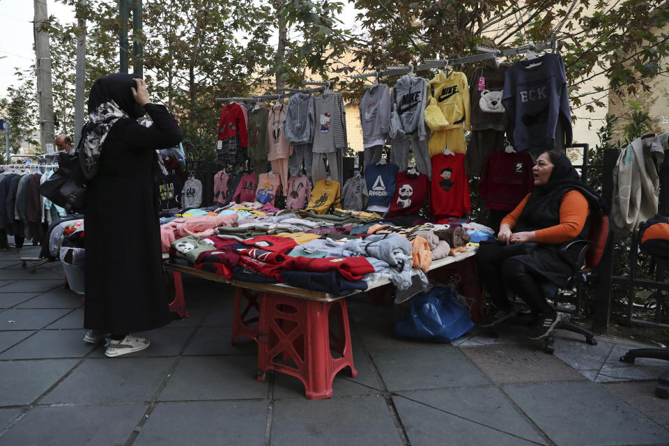 A street vendor talks with a customer in downtown Tehran, Iran, Monday, Nov. 1, 2021. As U.S. sanctions and the coronavirus pandemic wreak havoc on Iran's economy, suicides in the country increased by over 4%, according to a government study cited by the reformist daily Etemad. About 1 million Iranians have lost their jobs, and unemployment has climbed over 10% — a rate that is nearly twice as big among youths. (AP Photo/Vahid Salemi)