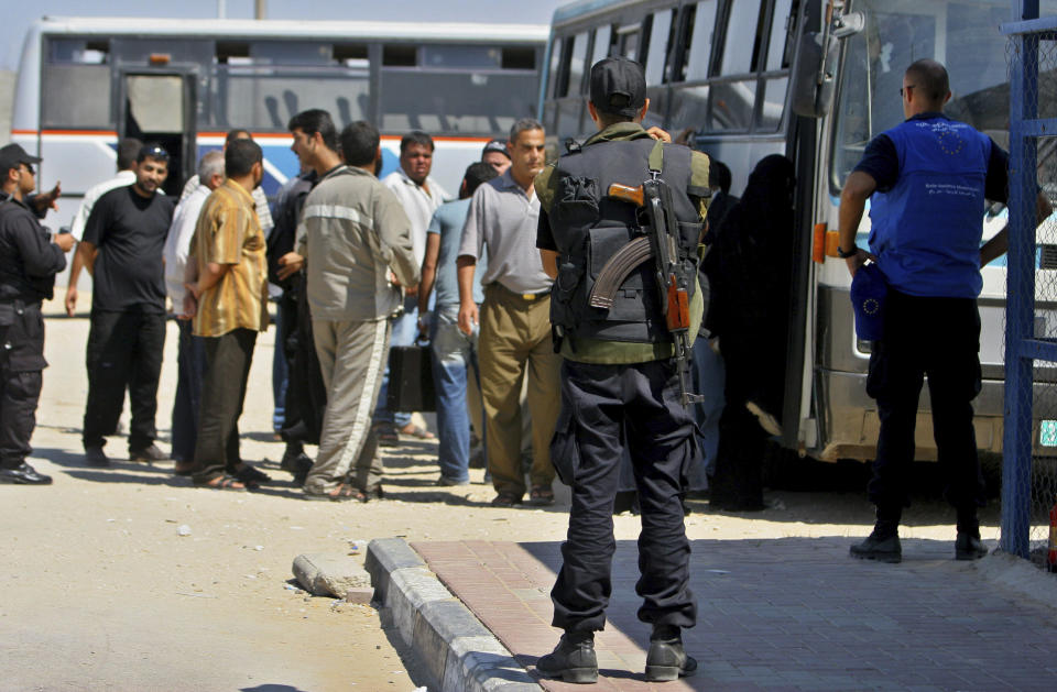 FILE - A member of Mahmoud Abbas' presidential guard and a European Union observer watch Palestinians board a bus before crossing the border from the Gaza Strip to Egypt at the Rafah border crossing Wednesday, Oct. 4, 2006. The European Union withdrew the monitoring mission formed to promote a two-state solution between Israel and the Palestinians from Gaza after the Hamas militant group seized power in 2007. But 16 years later, the mission continues to maintain offices in Israel in hopes of one day returning. Critics say the ongoing Western commitment to the two-state solution fails to recognize the changing circumstances in the region and maintains a costly-status quo. (AP Photo/Khalil Hamra, File)