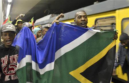 A man holds a South Africa flag at Johannesburg's Park Station on his way to the Memorial Service for former South African President Nelson Mandela at the First National Bank Stadium, also known as Soccer City December 10, 2013. REUTERS/Mujahid Safodien