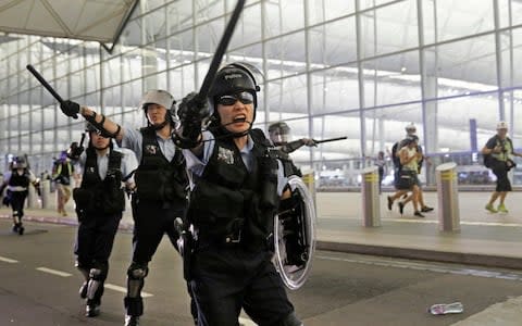 Police with batons and shields shout at protesters during a demonstration at the Chek Lap Kok Airport in Hong Kong, - Credit: Vincent Yu/AP