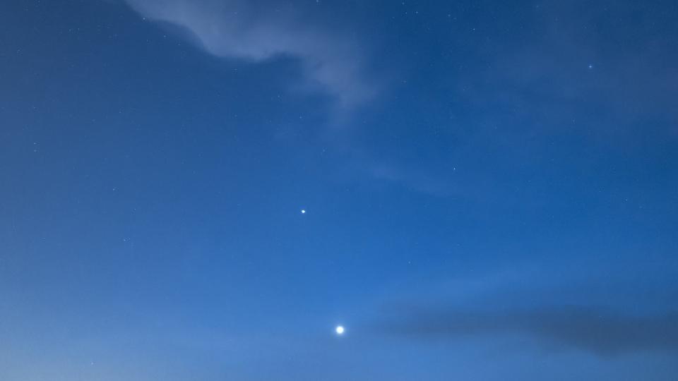 a dark blue sky with thin, cloudy clouds and two bright points of light, one of which is Venus and the other Mercury.