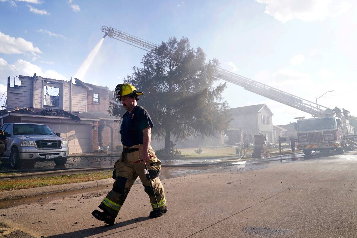 Firefighters from multiple departments work on putting out hot spots when a nearby grass fire damaged at least 26 homes Monday in Balch Springs.