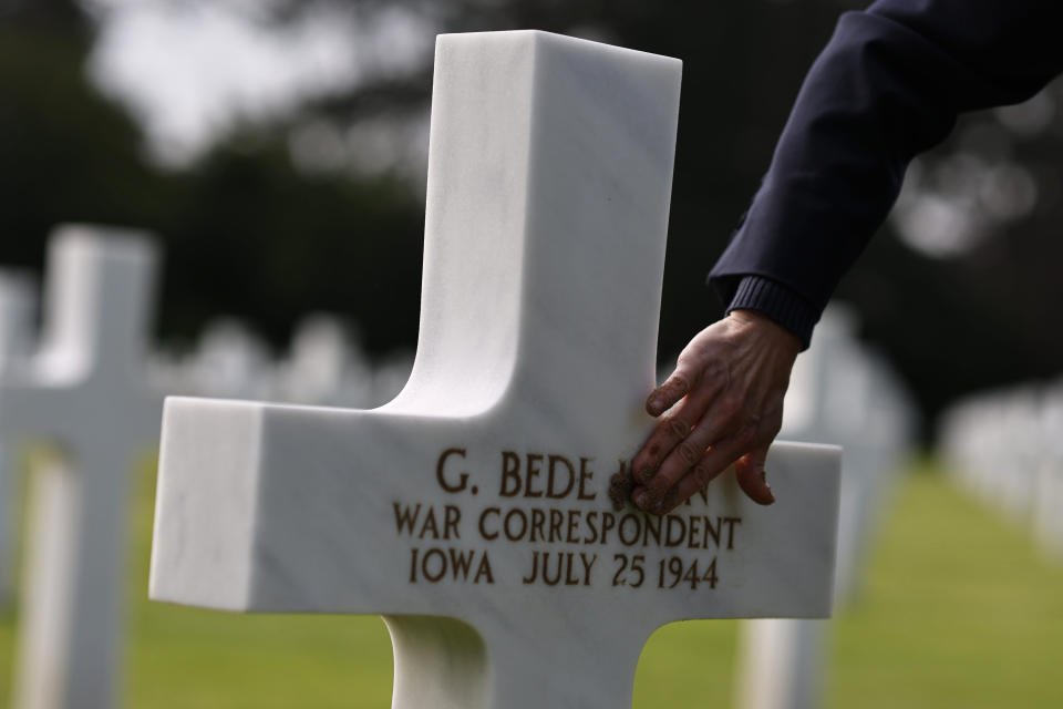 Muriel Rambert, interpretive guide at American Battle Monuments Commission, covers the grave of Associated Press photographer Bede Irvin with sand from Omaha Beach, at the Normandy American Cemetery in Colleville-sur-Mer, France on Monday, June 3, 2024. Bede Irvin was killed July 25, 1944 near the Normandy town of Saint-Lo as he was photographing an Allied bombardment. (AP Photo/Jeremias Gonzalez)